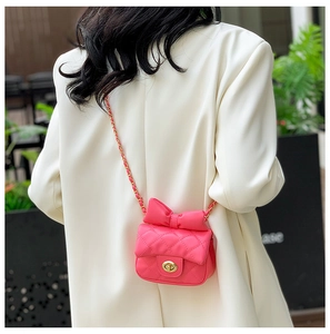 Detailed view of pink quilted mini bag with oversized bow and golden chain strap