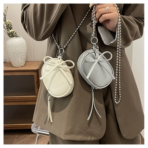 Detalle de mini bolsos bandolera con lazo y cadena de bolas metálicas en plata y crema