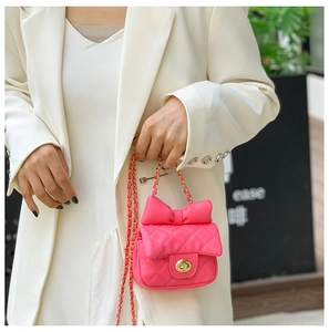 Detail of rose pink quilted mini bag with leather bow and gold twist lock chain