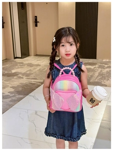 Pink sequin girls backpack with angel wings and pearl handle worn by a young model