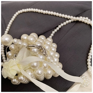 Detail of handmade pearl woven mini bag featuring a yellow satin drawstring pouch and bow
