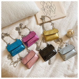 Assorted mini glitter chain bags in six colors arranged on a soft white texture background