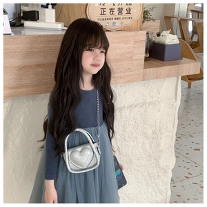 Detail of silver heart-shaped sequins crossbody bag with metallic chain on child model