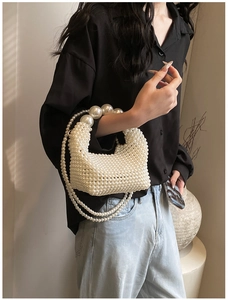 Detail of handmade cream white pearl woven bag with elegant top handle and crossbody chain