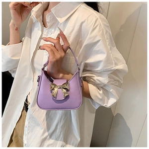 Détail du sac à main violet en cuir mat avec grand nœud en métal doré et forme de croissant
