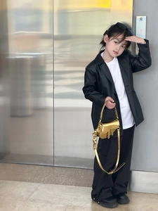 Close-up of golden metallic mini saddle bag with shiny finish worn by a child