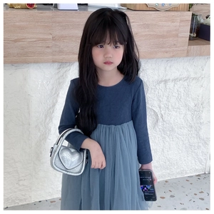 Detail of a sparkling silver sequin heart-shaped crossbody bag held by a young child model