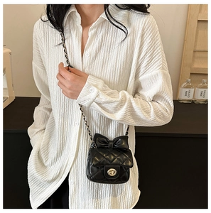 Close-up of a quilted black leather kids' crossbody bag with a cute bow and gold chain