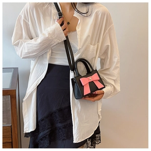 Dettaglio borsa nera per bambini con grande fiocco rosa e chiusura a cuore in metallo
