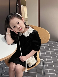 Detail of girls' black velvet dress with white lace collar and mini pearl crossbody bag