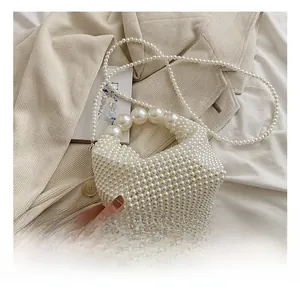 Detail of handmade pearl beaded handbag showing fine weave texture on white blazer