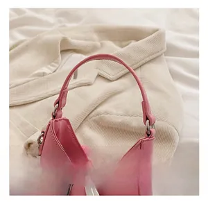 Détail du sac à main en cuir rose montrant la poignée et le nœud en métal argenté