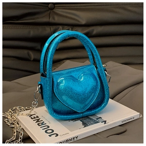 Detail of blue sequined heart crossbody bag for kids with silver chain strap on a magazine