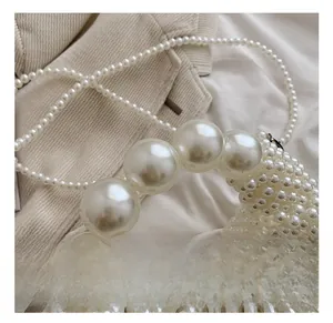 Detail of hand-woven pearl handbag with large spherical handle and intricate texture