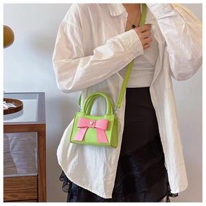 Borsa a tracolla verde neon per bambina con fiocco rosa indossata dal modello