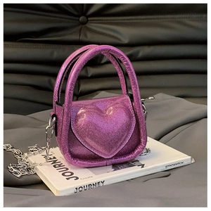 Macro detail of purple glitter heart shaped bag with silver metal chain and sequins