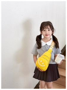 Close-up of bright yellow kids' crossbody chest bag featuring a white smiley face and fashion strap