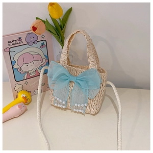 Detail of handmade straw bag featuring a large blue organza bow and white pearl accents