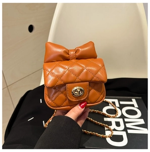 Detail of orange quilted kids crossbody bag with bow decoration and gold twist lock