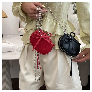 Detalle de mini bolsos ovalados en rojo y negro con lazos y correas de cadena plateada