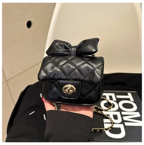 Close-up of black quilted kid shoulder bag with leather bow and gold twist lock