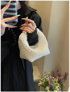 Detail of hand-woven white pearl handbag showing smooth bead texture and large sphere handles