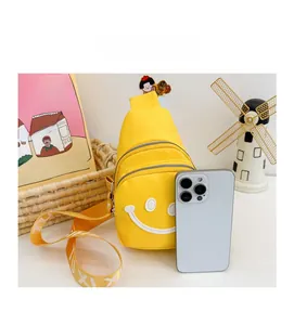 Yellow kids chest bag with smiley patch compared to a phone for scale and size