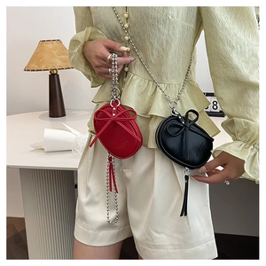 Detalle de mini bolsos bandolera con lazo en rojo y negro y cadenas de bolas metálicas