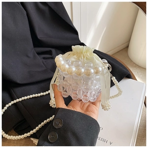 Detailed macro of a woven bead bucket bag with large pearl handle and satin drawstring lining