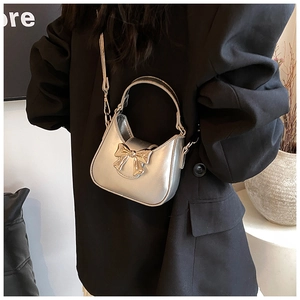 Détail du mini sac argenté avec nœud et chaîne porté sur une veste de costume noire