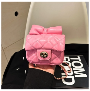 Detail of pink quilted mini crossbody bag with a large bow and gold rotary lock buckle