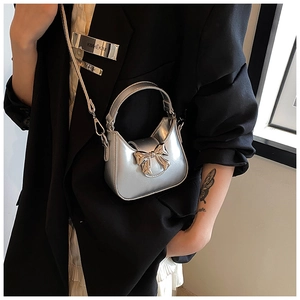 Détail d'un mini sac argenté avec un grand nœud et une fine bandoulière sur veste