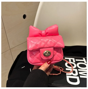 Detail of pink quilted mini bag with bow decoration and gold metal chain strap