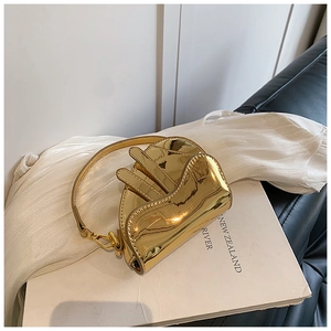 Top-down view of a shiny gold metallic saddle bag on a white textured fabric background