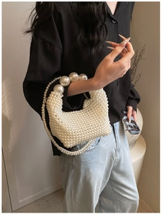 Detail of handmade woven pearl handbag featuring double beaded handles on a model