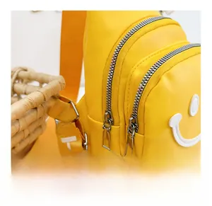 Detail view of the yellow kids' crossbody bag featuring a smooth zipper and smiley patch