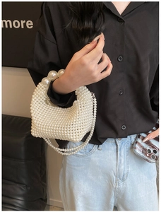 Detail of hand-woven pearl handbag with large decorative beads and a long strap