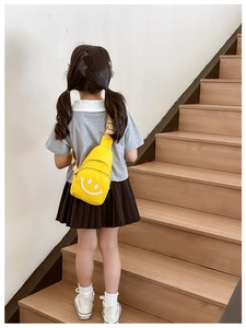 Detailed view of yellow kids chest bag with smiley face logo on adjustable strap back
