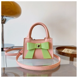 Dettaglio borsa rosa per bambina con grande fiocco verde e fibbia in metallo a cuore