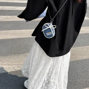 Detail of mini blue denim round bag with white bow and rainbow patch on silver chain