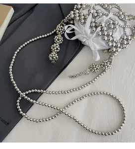 Detail of silver beaded crossbody bag featuring a white satin drawstring inner pouch