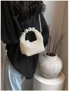 Detail of hand-woven pearl handbag with large bead handle and elegant shoulder strap