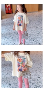 Close-up of kids summer outfit featuring a cream monster print T-shirt and pink slim trousers