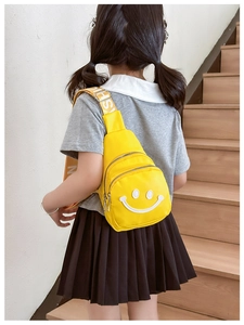 Detail of a bright yellow kids chest bag featuring a smiley face and fashion strap