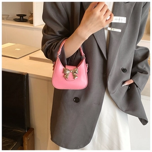 Mini sac à main rose avec nœud argenté tenu par un mannequin au bureau