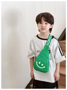 Close-up of green kids chest bag featuring a white smile face and FASHION logo strap