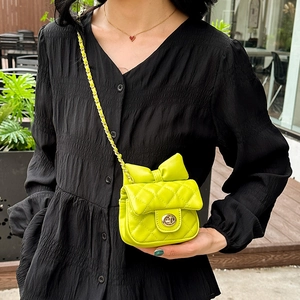 Kids quilted neon crossbody bag with bow detail and gold chain strap shown on model