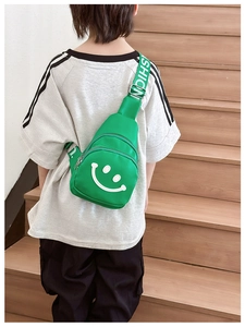 Green nylon kids chest bag with smiley face print worn by child on wooden stairs