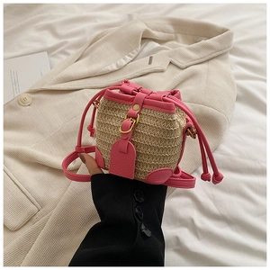 Détail des finitions en similicuir rose et paille tressée du sac seau enfant