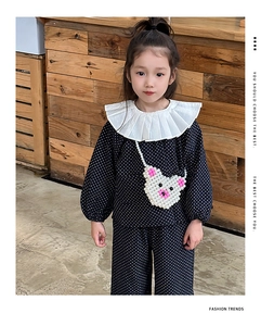 Detail einer süßen Bären-Tasche aus Perlen auf einem gepunkteten Kinder-Outfit im Set